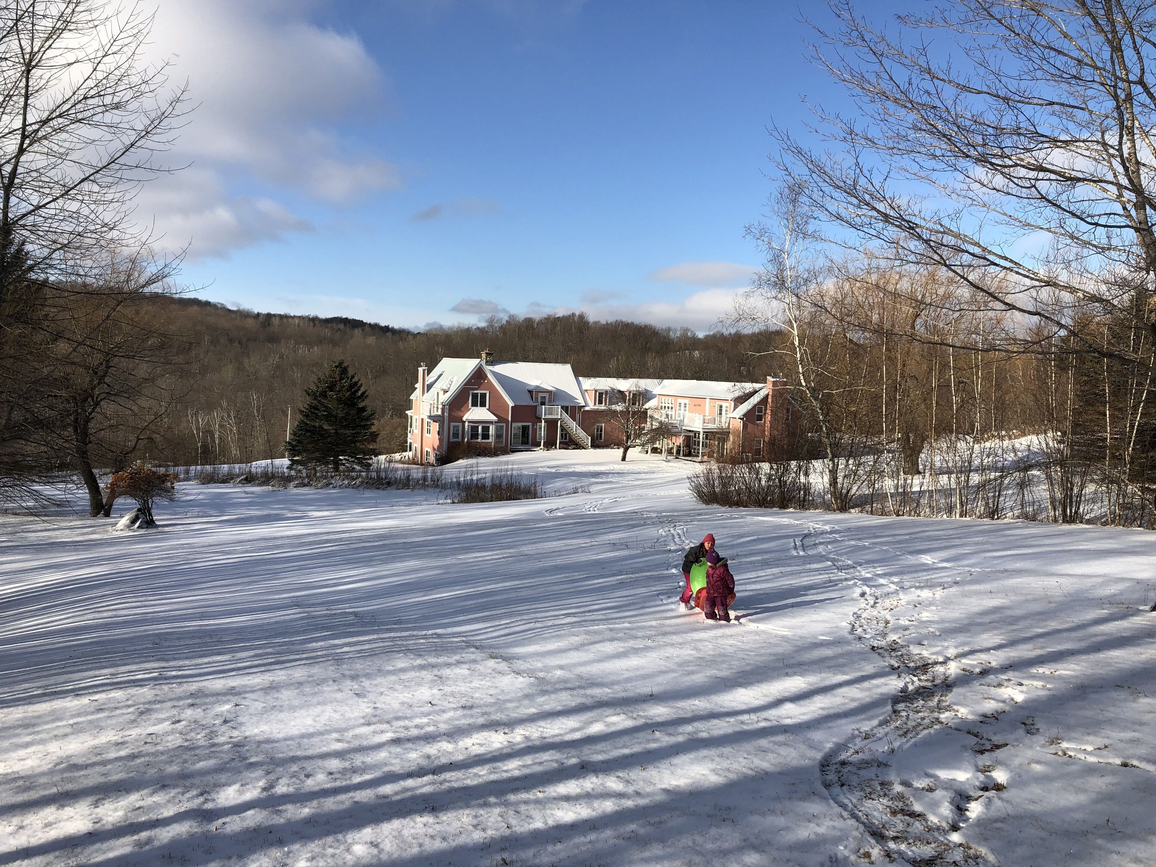 A snow-covered landscape with a large house in the background.