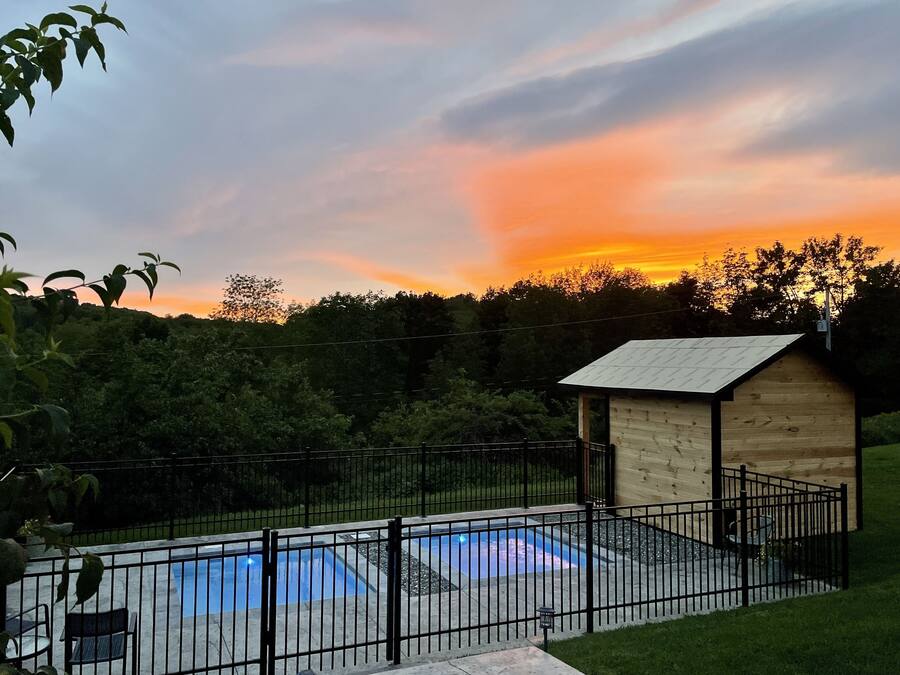 A wooden cabin with a metal roof, a swimming pool, and a fenced yard.