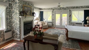 A bedroom with a fireplace, a bed, a sofa, and a dining table. - Auberge Le Tricorne (Hatley)