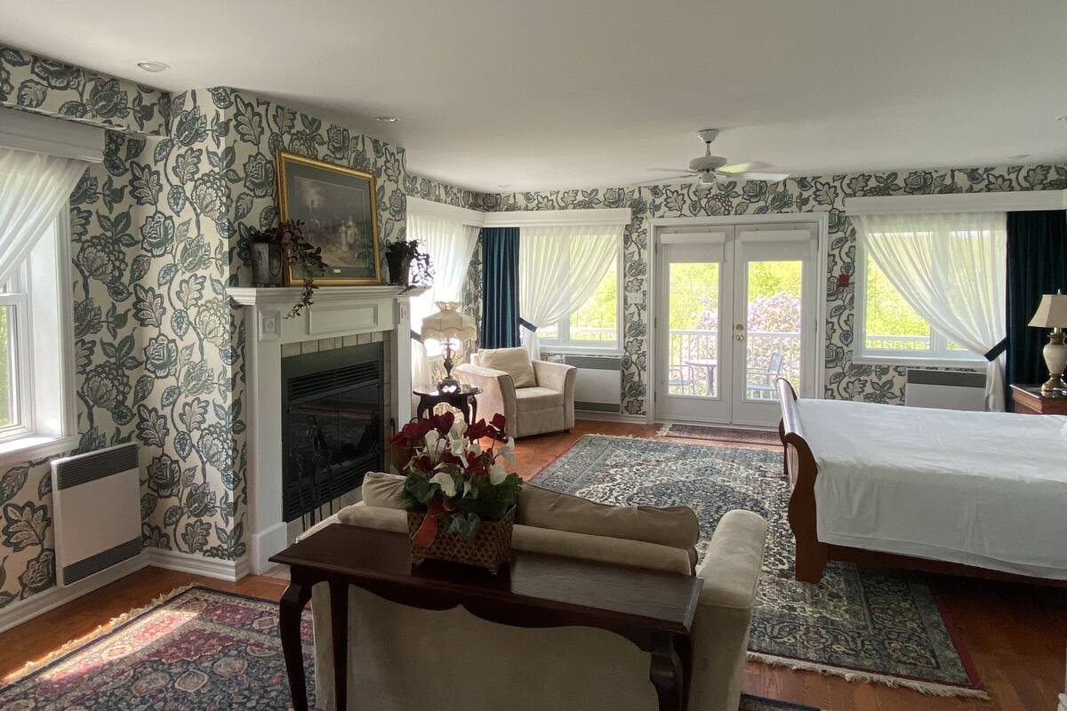 A bedroom with a fireplace, a bed, a sofa, and a dining table.