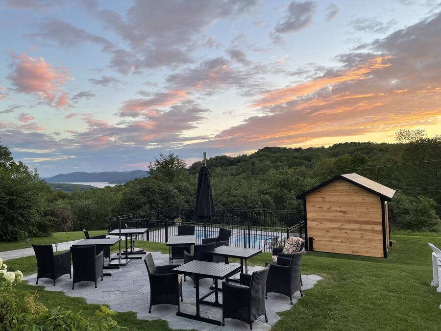 An outdoor patio with tables and chairs, a wooden shed, and a pool.