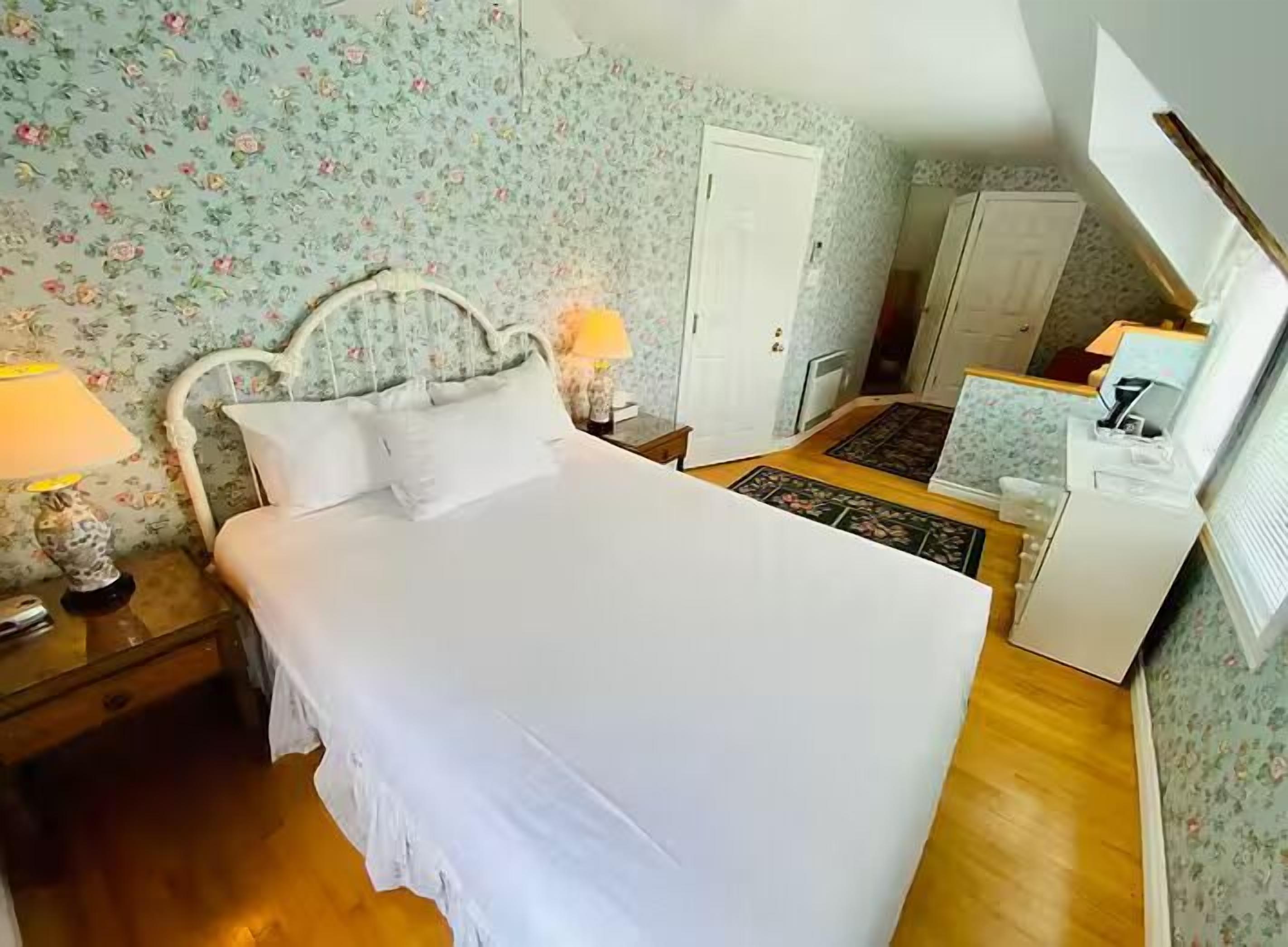A bedroom with a bed, two bedside tables, a nightstand, a dresser, a desk, and a lamp.