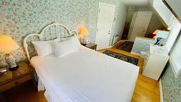 A bedroom with a bed, two bedside tables, a nightstand, a dresser, a desk, and a lamp.