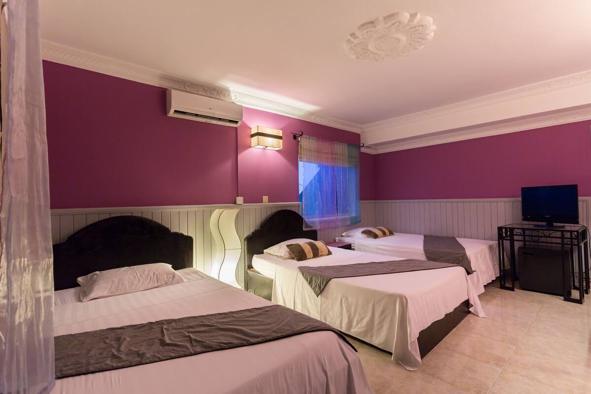 A hotel room with two beds, a television, and an air conditioning unit.