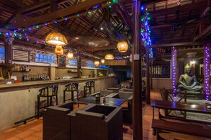 Ein Restaurant mit Korbmöbeln, einer Bar und einer Buddha-Statue.