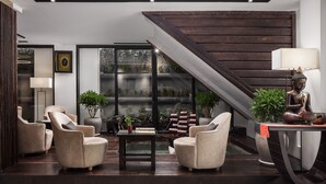 Un salon moderne avec un escalier, des sièges confortables et une statue de Bouddha.
