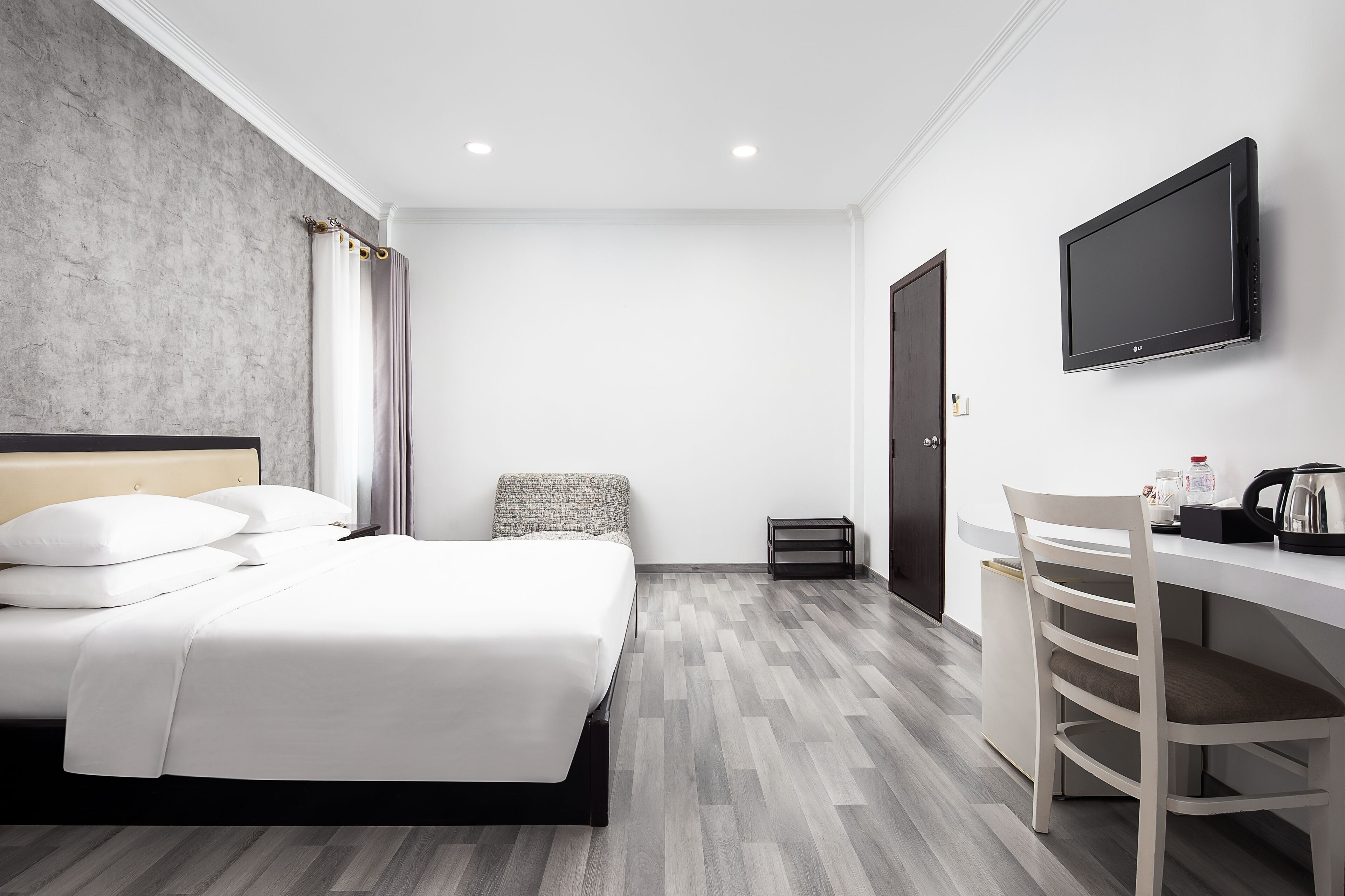 Une chambre d’hôtel équipée d’un lit, d’un bureau, d’une chaise, d’une télévision et d’une petite poubelle.