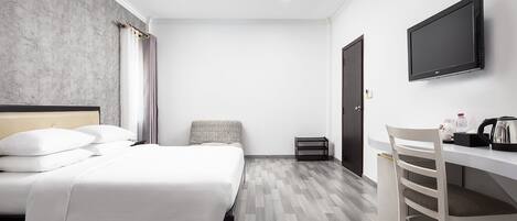 Une chambre d’hôtel équipée d’un lit, d’un bureau, d’une chaise, d’une télévision et d’une petite poubelle.