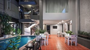 Un espace piscine intérieur moderne, comprenant une piscine, des sièges et des plantes en pot.