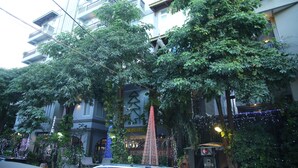 Un immeuble à plusieurs étages doté de balcons, une enseigne indiquant la présence d’un hôtel et des guirlandes lumineuses.
