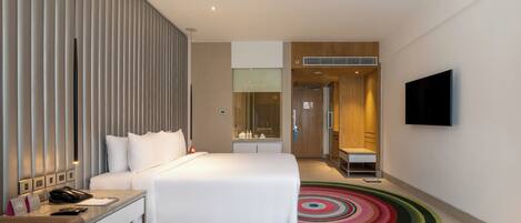 A modern hotel room with a bed, bedside table, and a TV mounted on the wall.