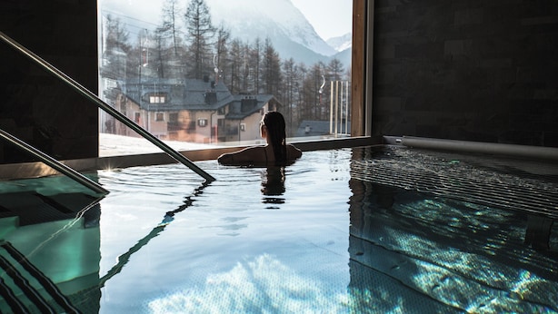 Une piscine intérieure avec vue sur une montagne et des arbres.