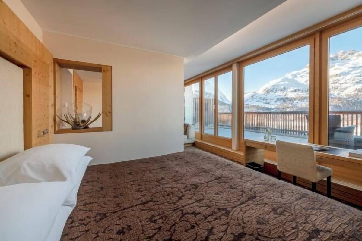 Een slaapkamer met een groot bed, een bureau en uitzicht op bergen.