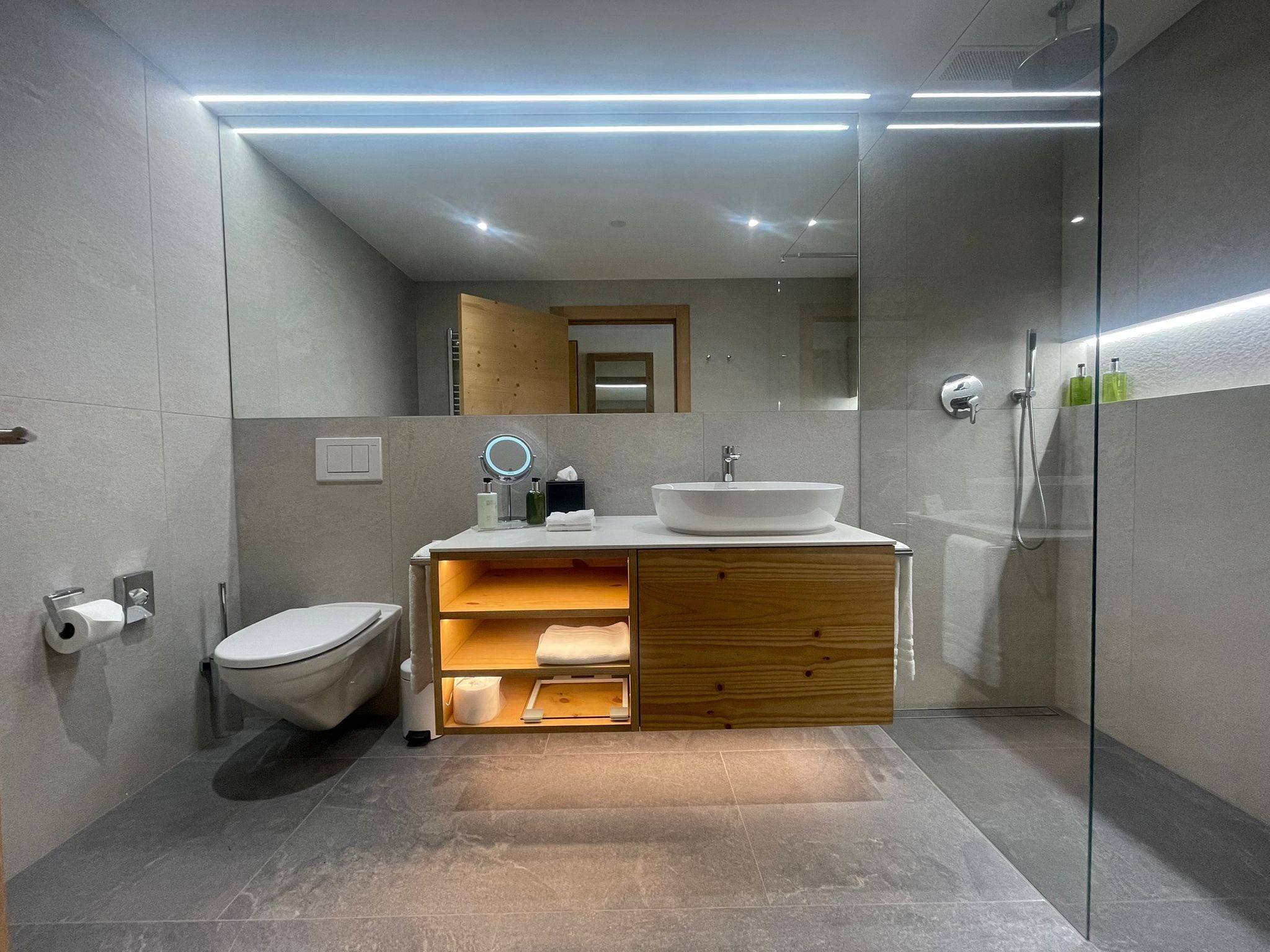 A modern bathroom with a toilet, sink, and shower.