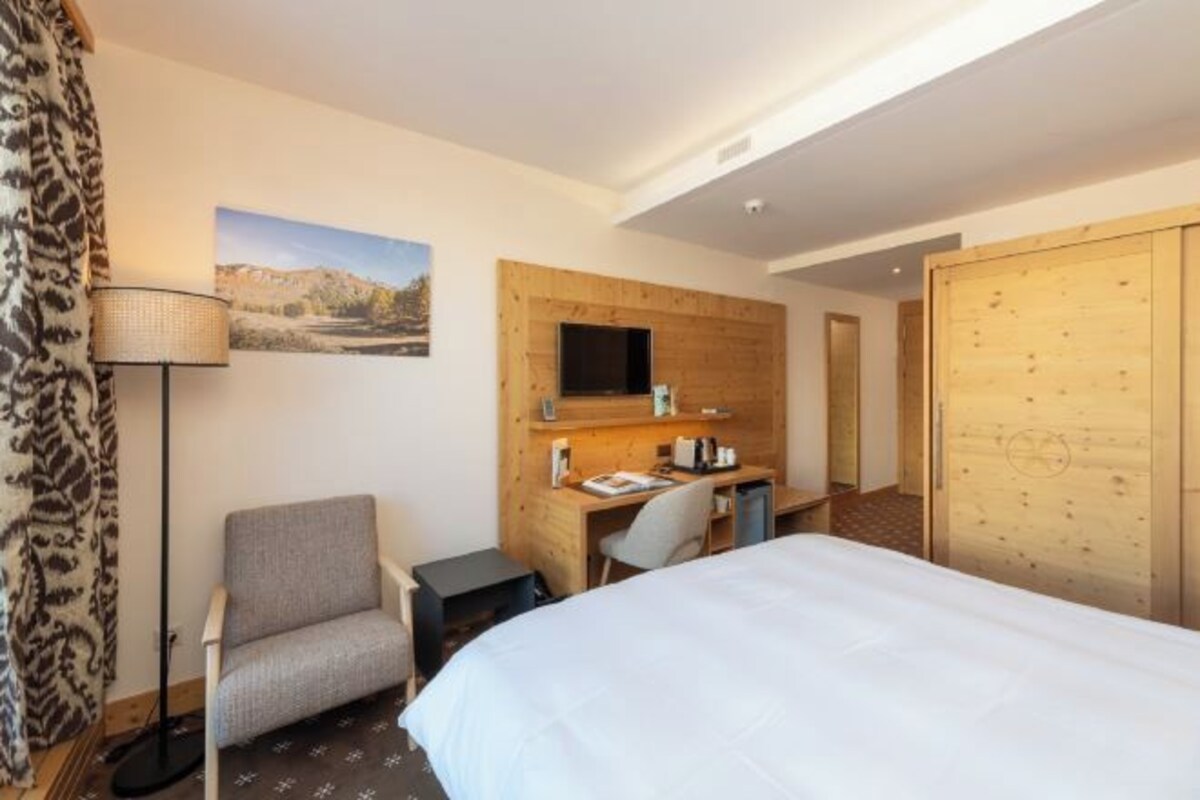 Een hotelkamer met een bed, een bureau met stoel, een televisie en een kledingkast.