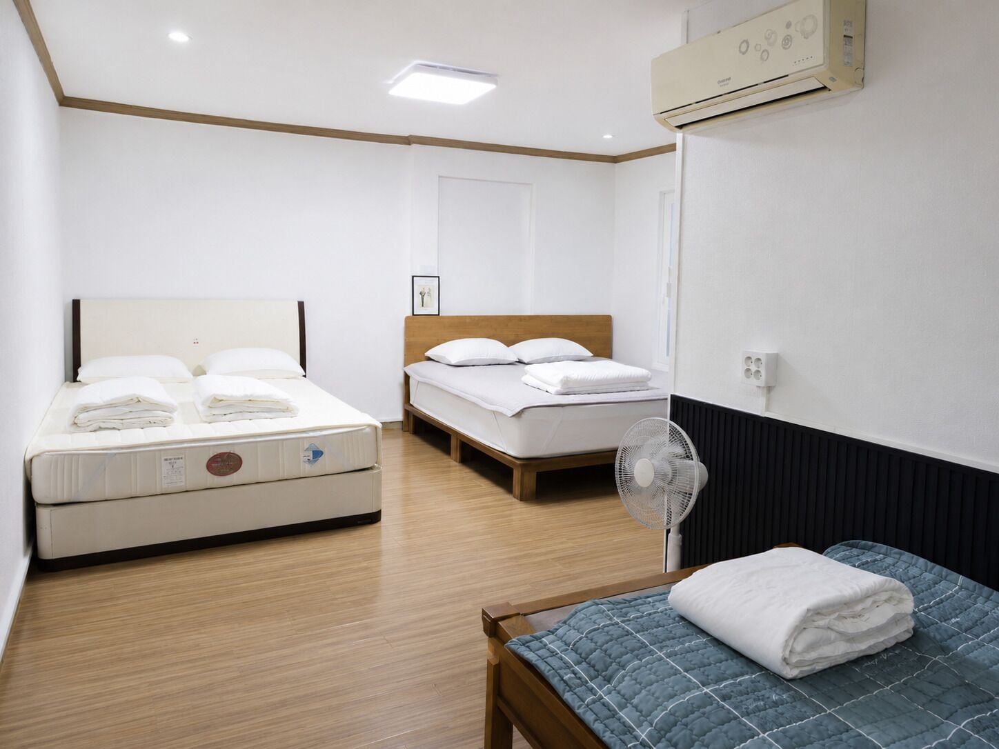 Una habitación de hotel con una cama, una mesita de noche, un ventilador y una ventana.