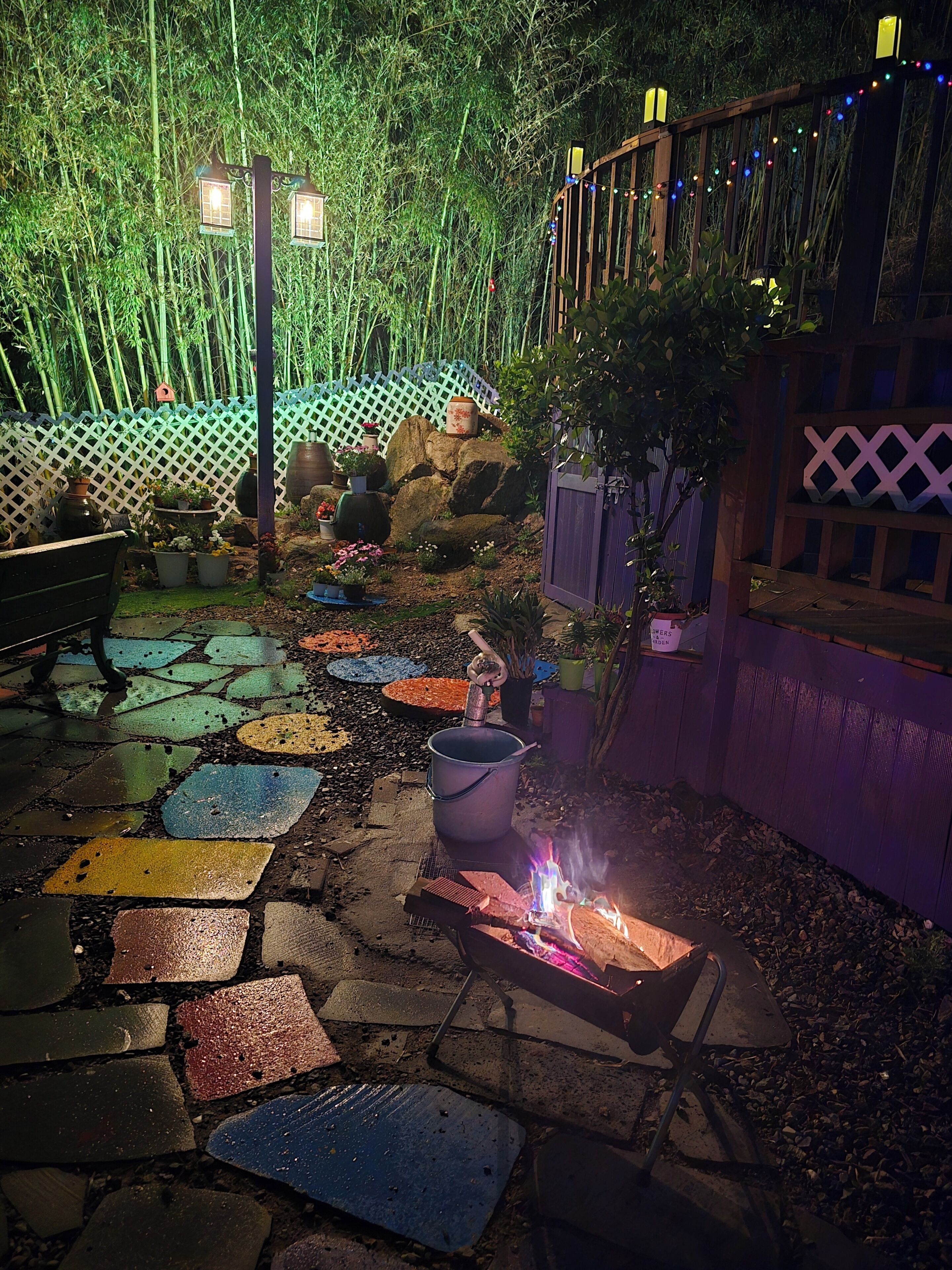 A garden patio with a fire pit, decorative tiles, and a wooden fence.