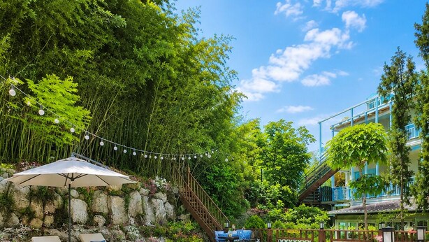 Une piscine avec des chaises longues, une terrasse en bois et un mur en pierre.