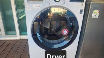A front view of a white LG TROMM dryer with a digital display and control panel, placed on a wooden deck.