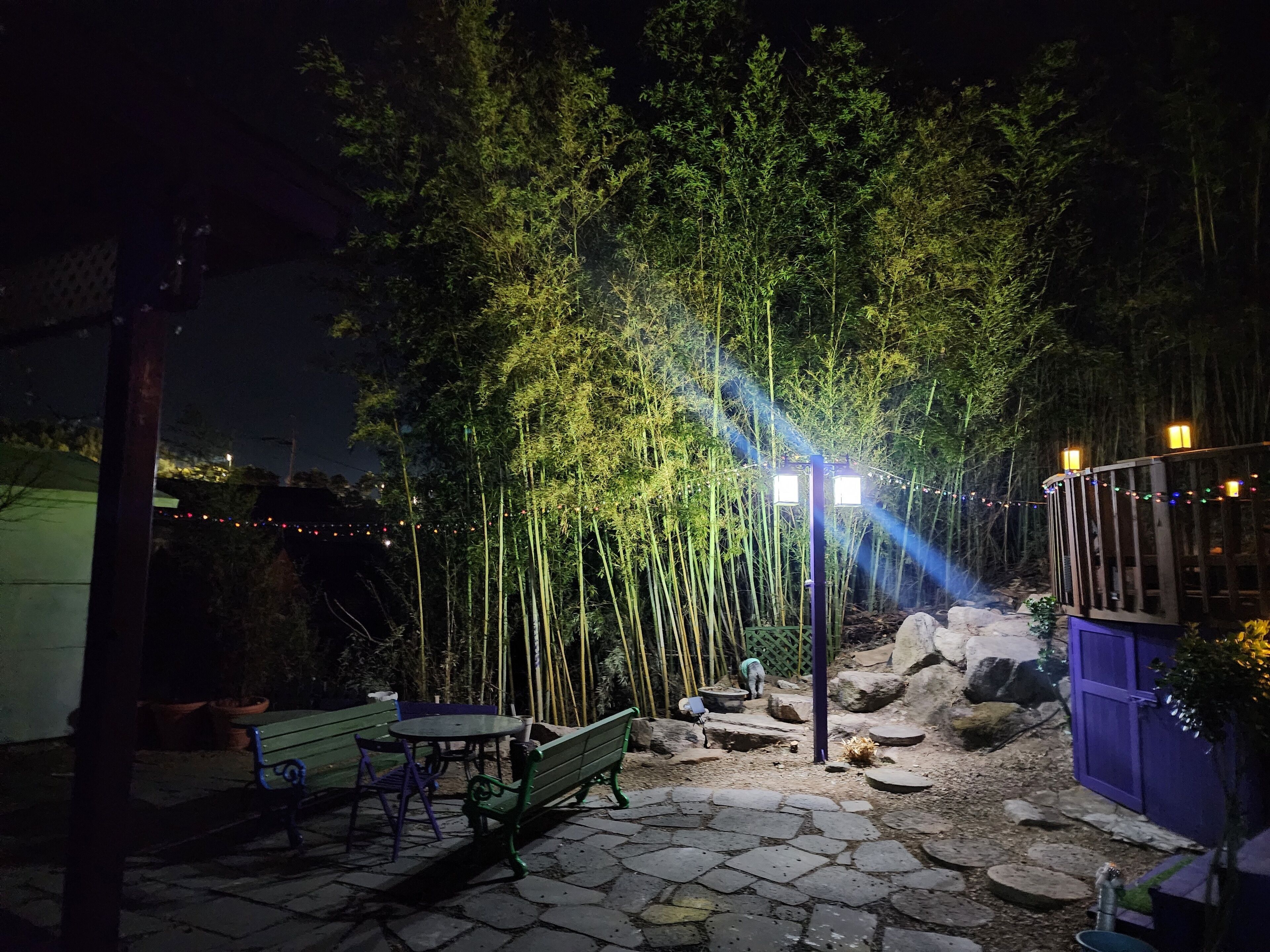An outdoor patio area with stone flooring, a green bench, and a table.