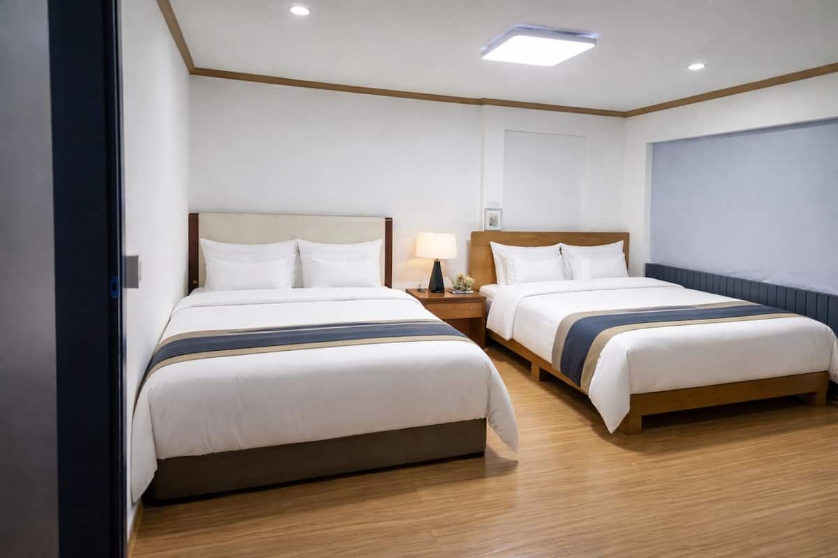 Une chambre d’hôtel avec deux lits, un plancher en bois et une grande fenêtre.