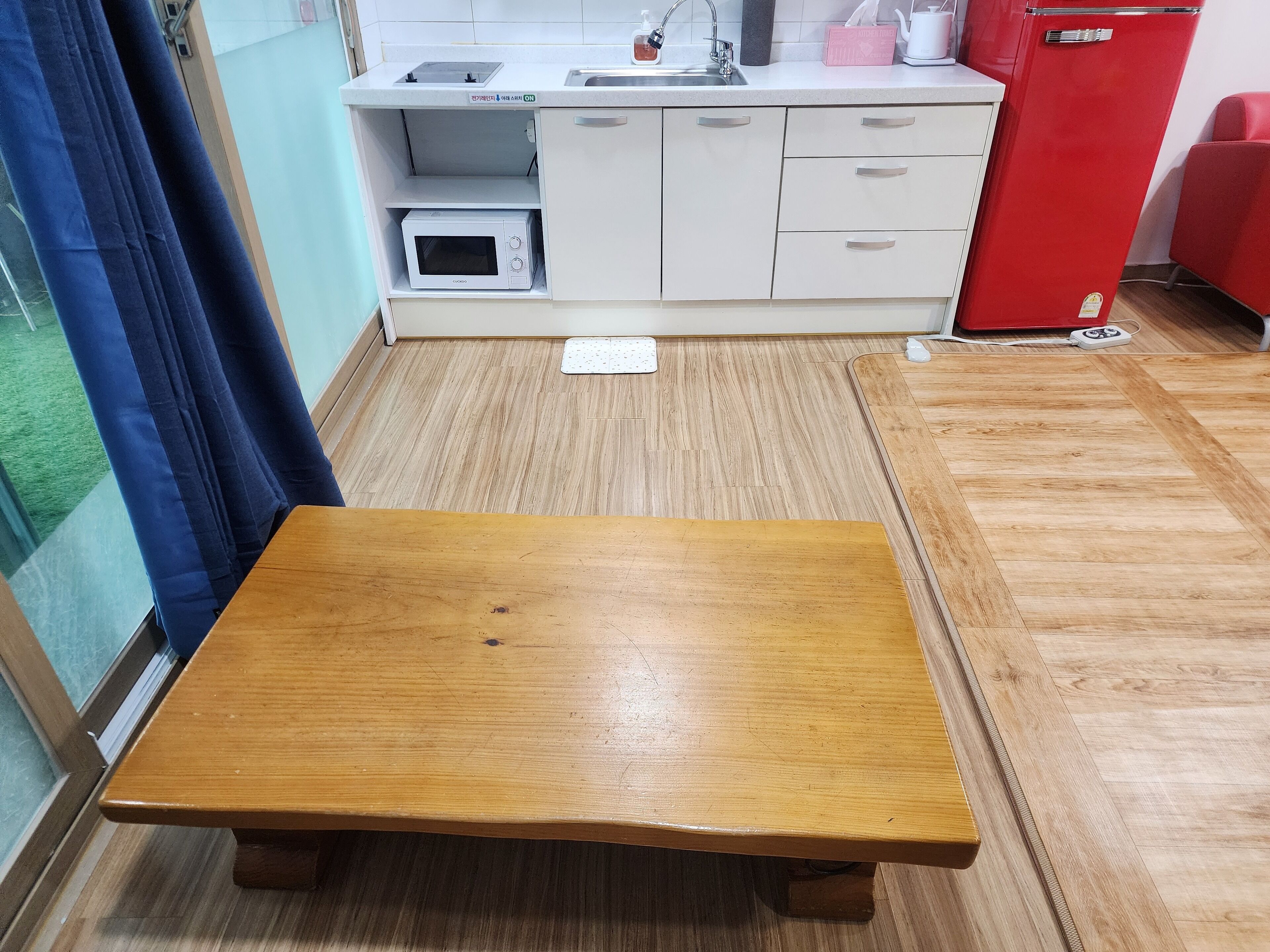 A small kitchen with a microwave, sink, and a red refrigerator.