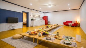 Un salon moderne comprenant un coin repas, un téléviseur et un canapé rouge.