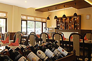 A restaurant with a bar area, wooden chairs, and tables set for dining.