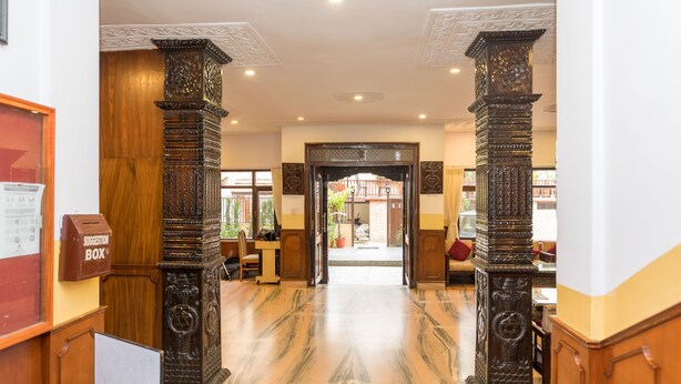A lobby with marble flooring, ornate pillars, a suggestion box, and a view into the adjacent room. - Hotel Thamel (Kathmandu)