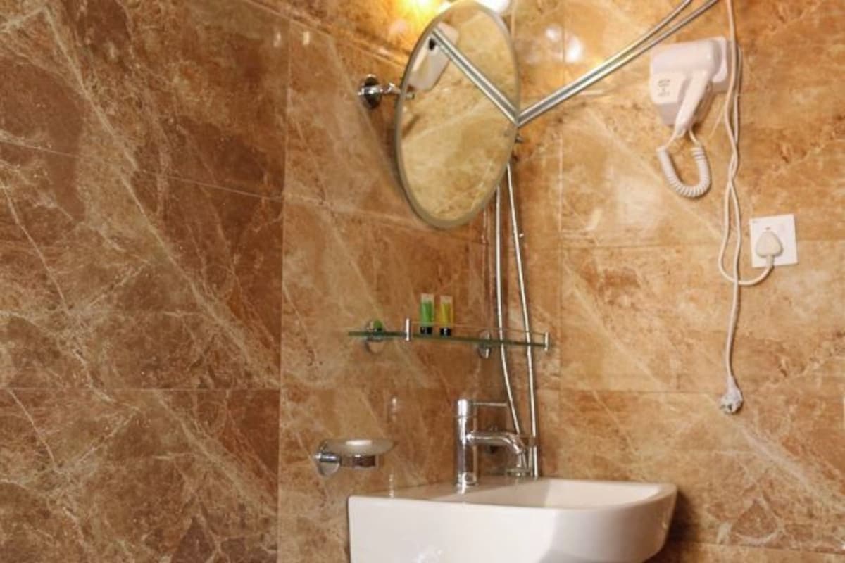 Un baño con pared de mármol, un lavabo, un espejo y un secador de pelo sobre un soporte de pared.