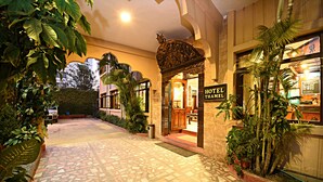 A hotel entrance with a tiled pathway leading to the door, surrounded by greenery and a decorative archway. - Hotel Thamel (Kathmandu)