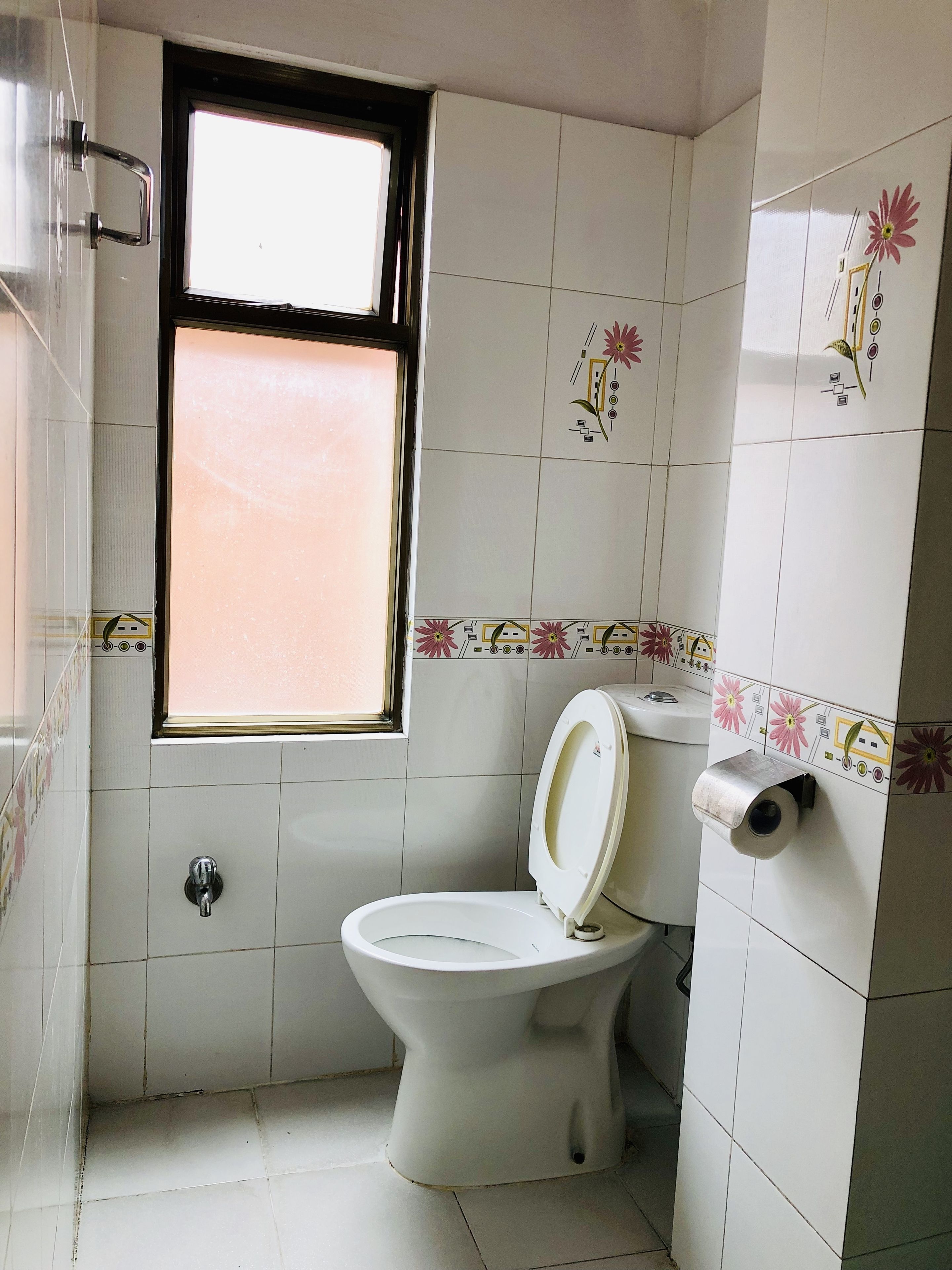 Une petite salle de bain avec des toilettes, une fenêtre et un porte-rouleau de papier toilette.