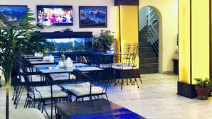 A restaurant with tables and chairs, a large aquarium, and a staircase. - Backyard Hotel (Kathmandu)