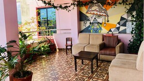 A living room with a patterned floor, a sofa, a small table, and a potted plant. - Backyard Hotel (Kathmandu)