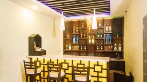 A bar area with wooden chairs and a bar counter, shelves with bottles, and pendant lights. - Backyard Hotel (Kathmandu)
