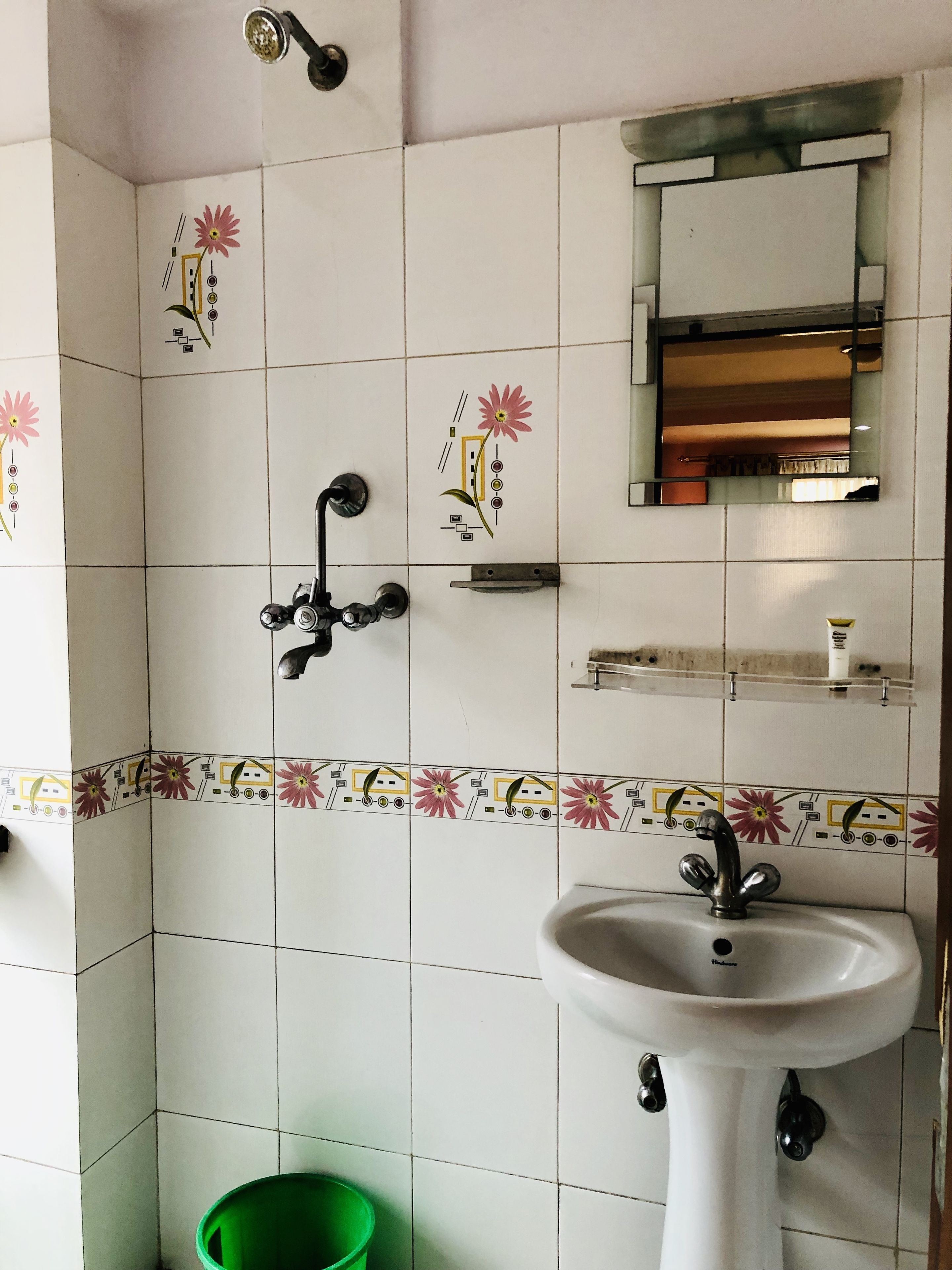 Une salle de bain avec un lavabo blanc, un miroir et une douche.
