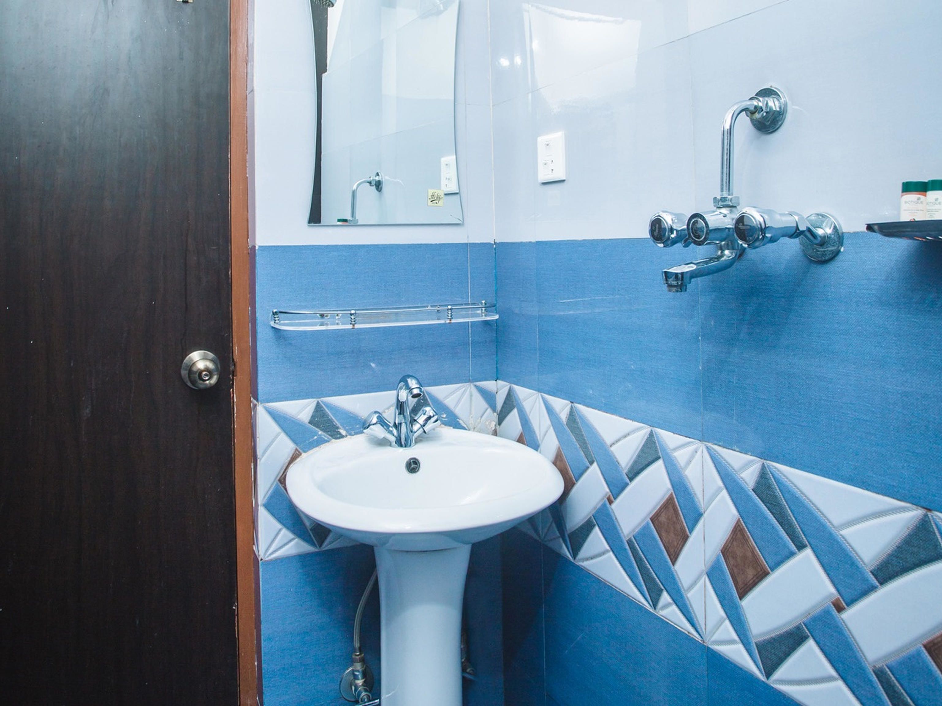 A bathroom with a white sink, blue and white patterned tiles, a mirror, and a shower with a chrome faucet.