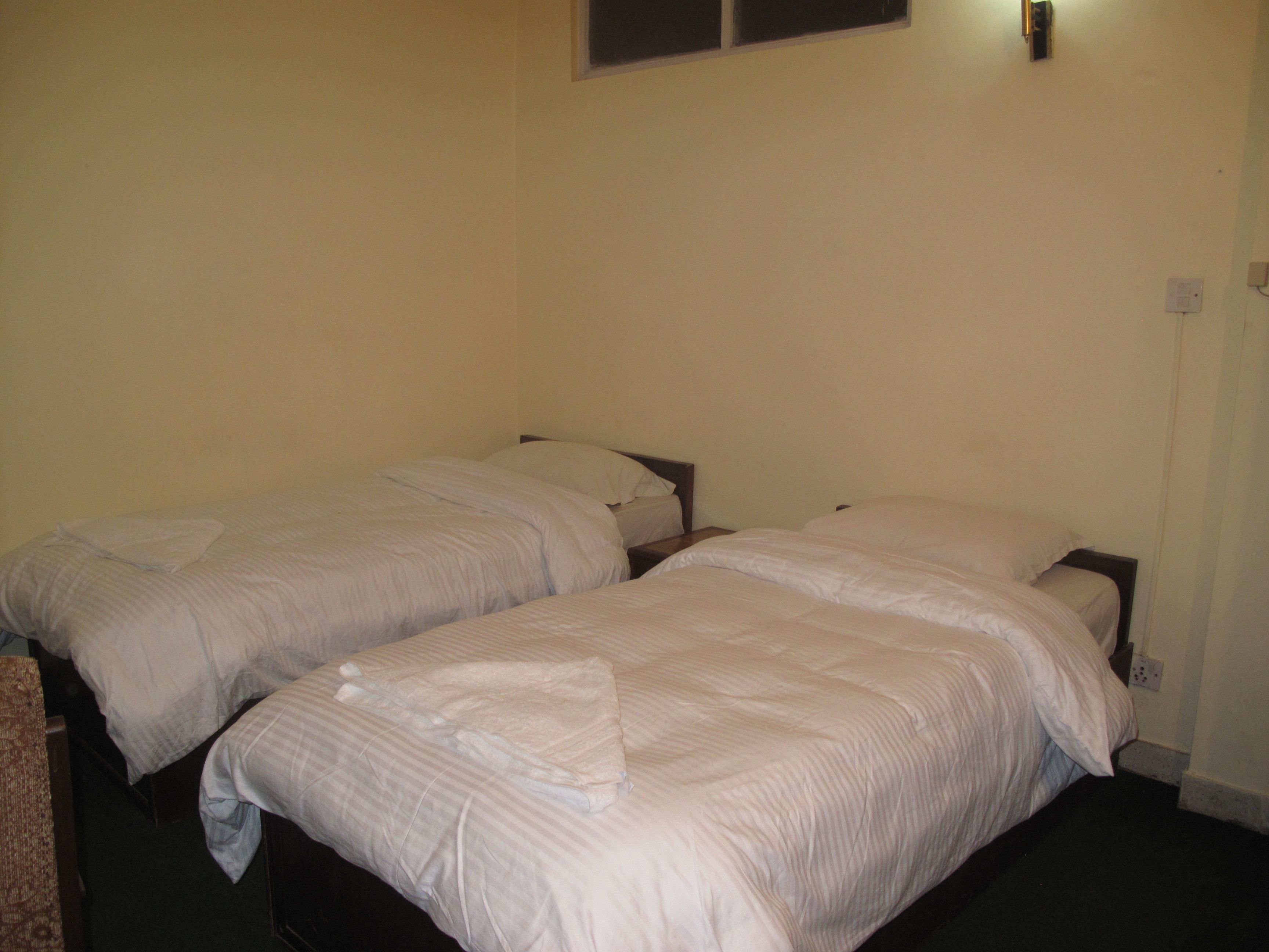Une chambre avec deux lits simples, chacun doté d’une tête de lit en bois et de draps blancs.