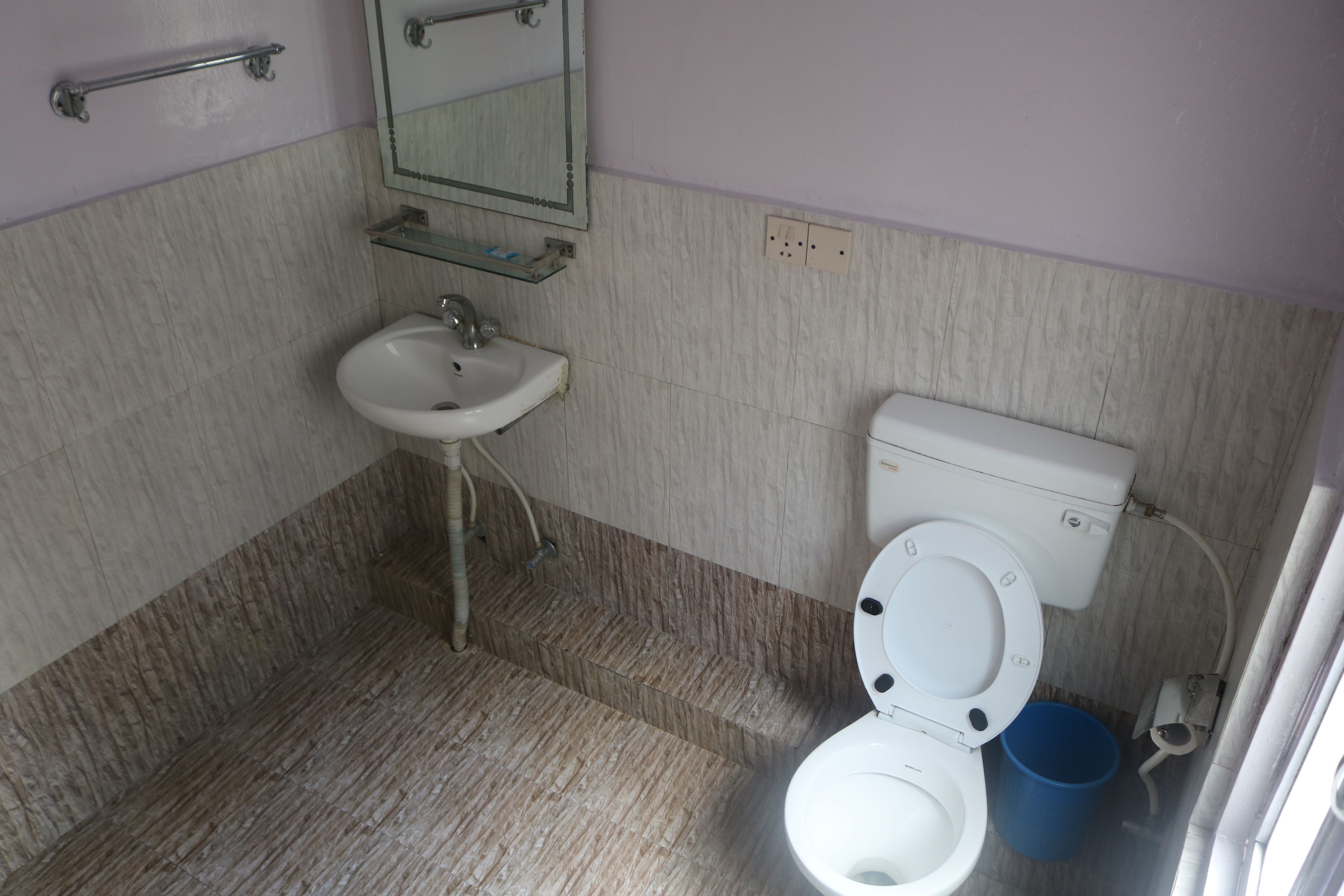Un baño con lavamanos, inodoro y espejo.