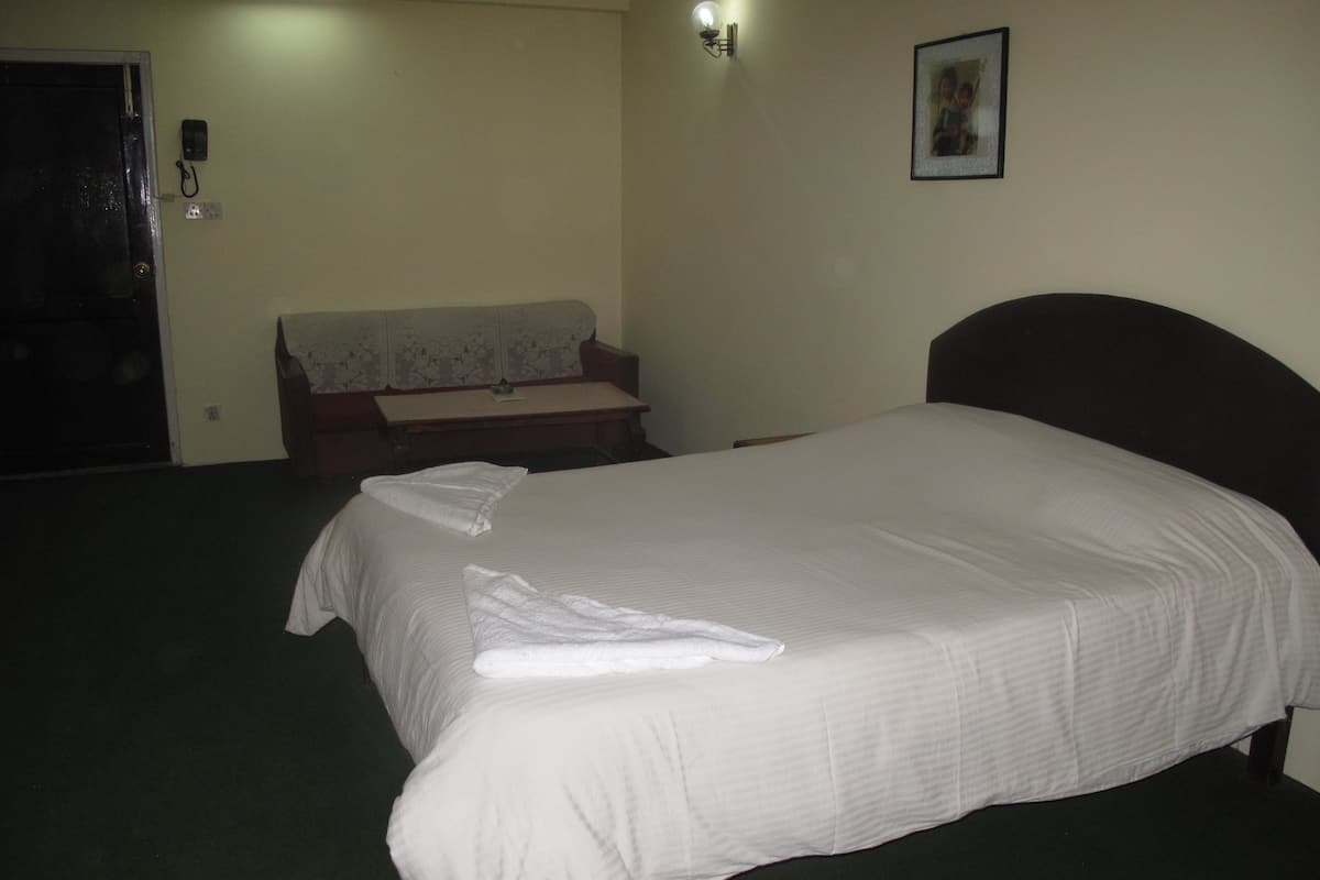 Ein Hotelzimmer mit Bett, einer Couch, einem Schreibtisch und einem an der Wand montierten Telefon.