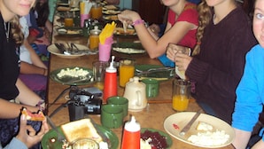 Una mesa de comedor con diferentes platos, cubiertos y bebidas.