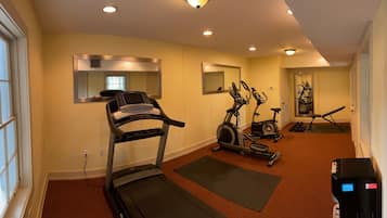 A hotel room with a treadmill, stationary bikes, and a massage chair.