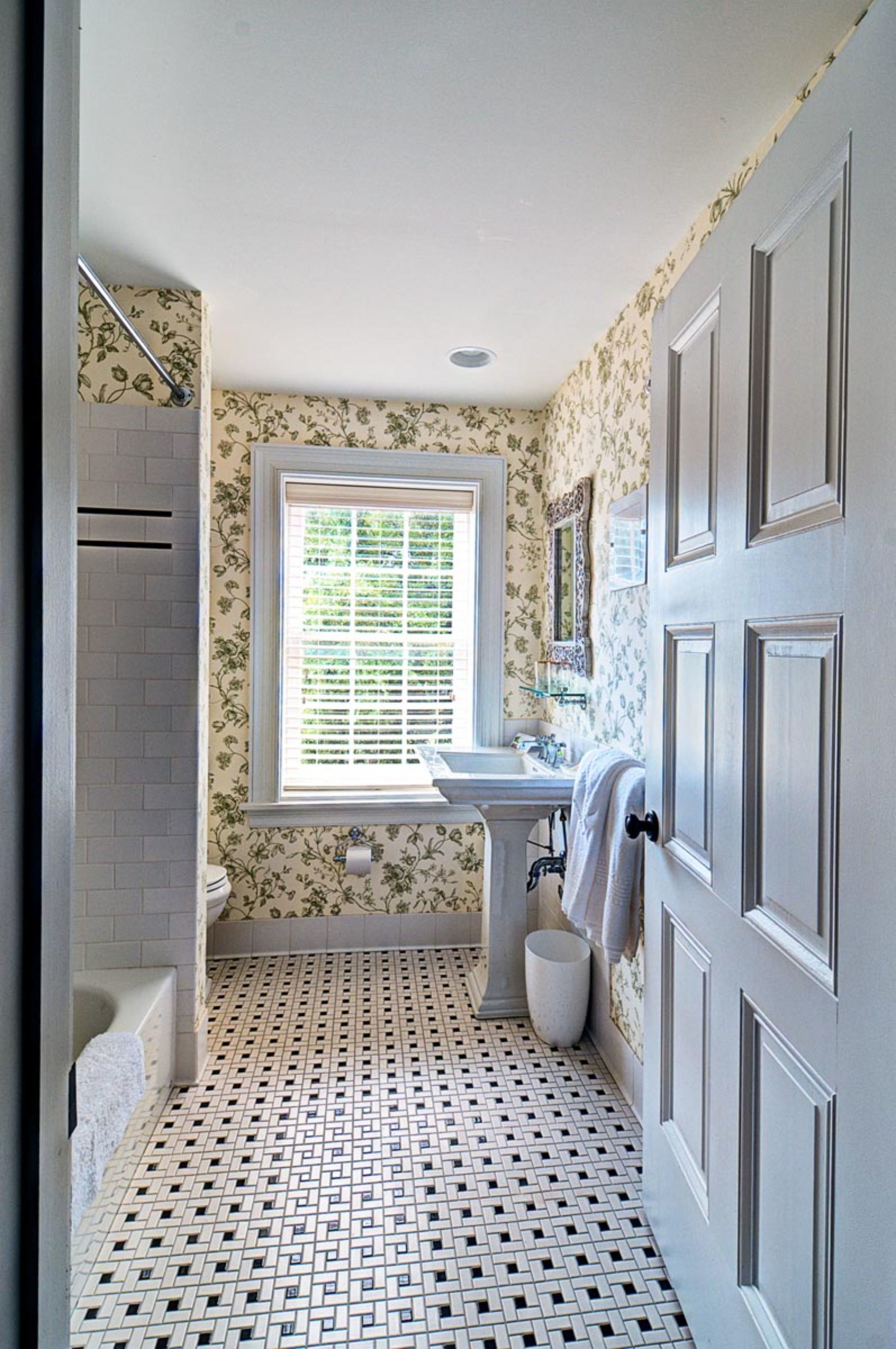 A bathroom with a patterned floor, a window, a sink, and a bathtub.