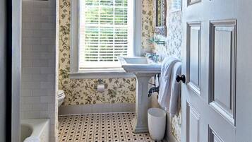 Une salle de bain avec un carrelage décoratif, une fenêtre, un lavabo et une baignoire.