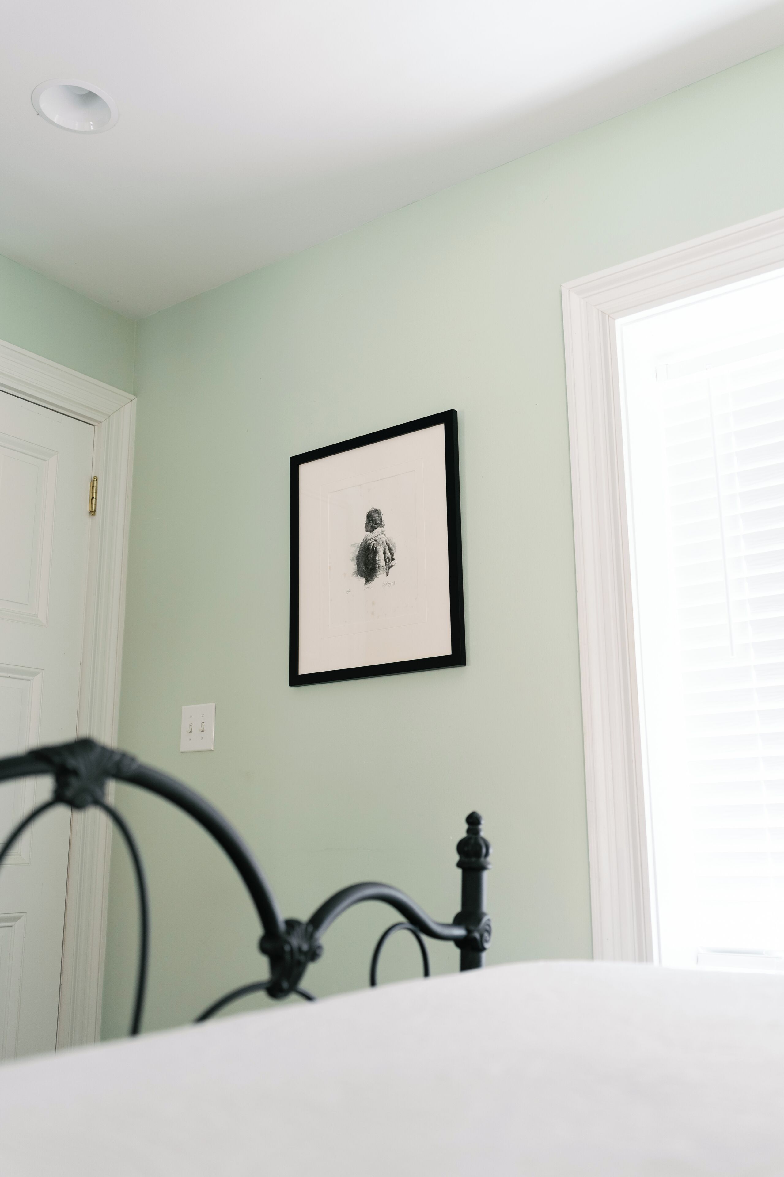 A bedroom with a bed, a framed picture on the wall, and a door.
