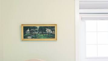Quarto com escrivaninha, cadeira e um quadro na parede.