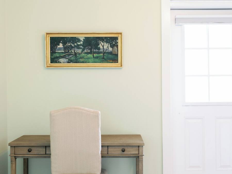 Quarto com escrivaninha, cadeira e um quadro na parede.
