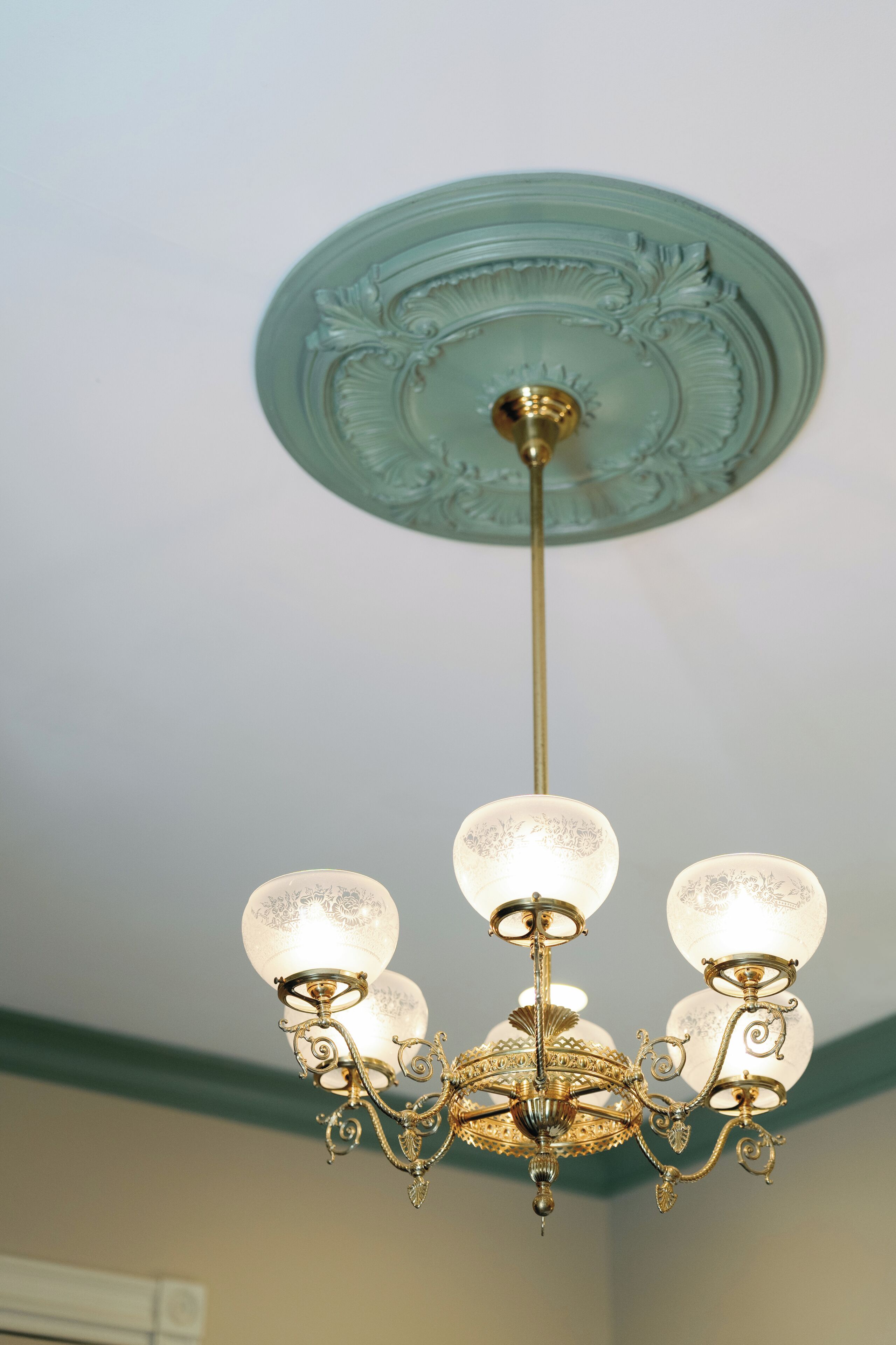 Un candelabro con tres globos de vidrio y ornamentación metálica.
