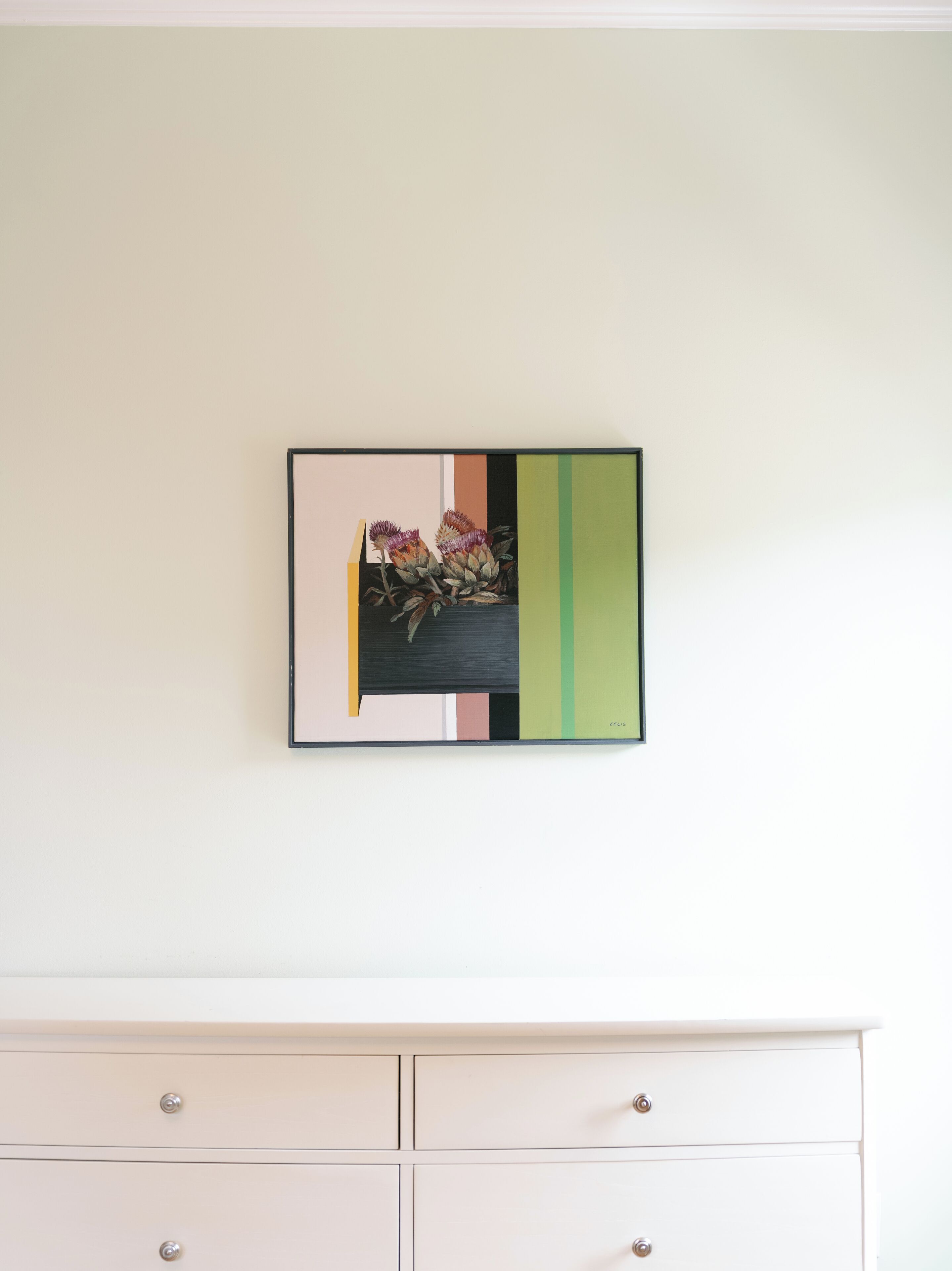 A framed artwork with a floral design on a wall.