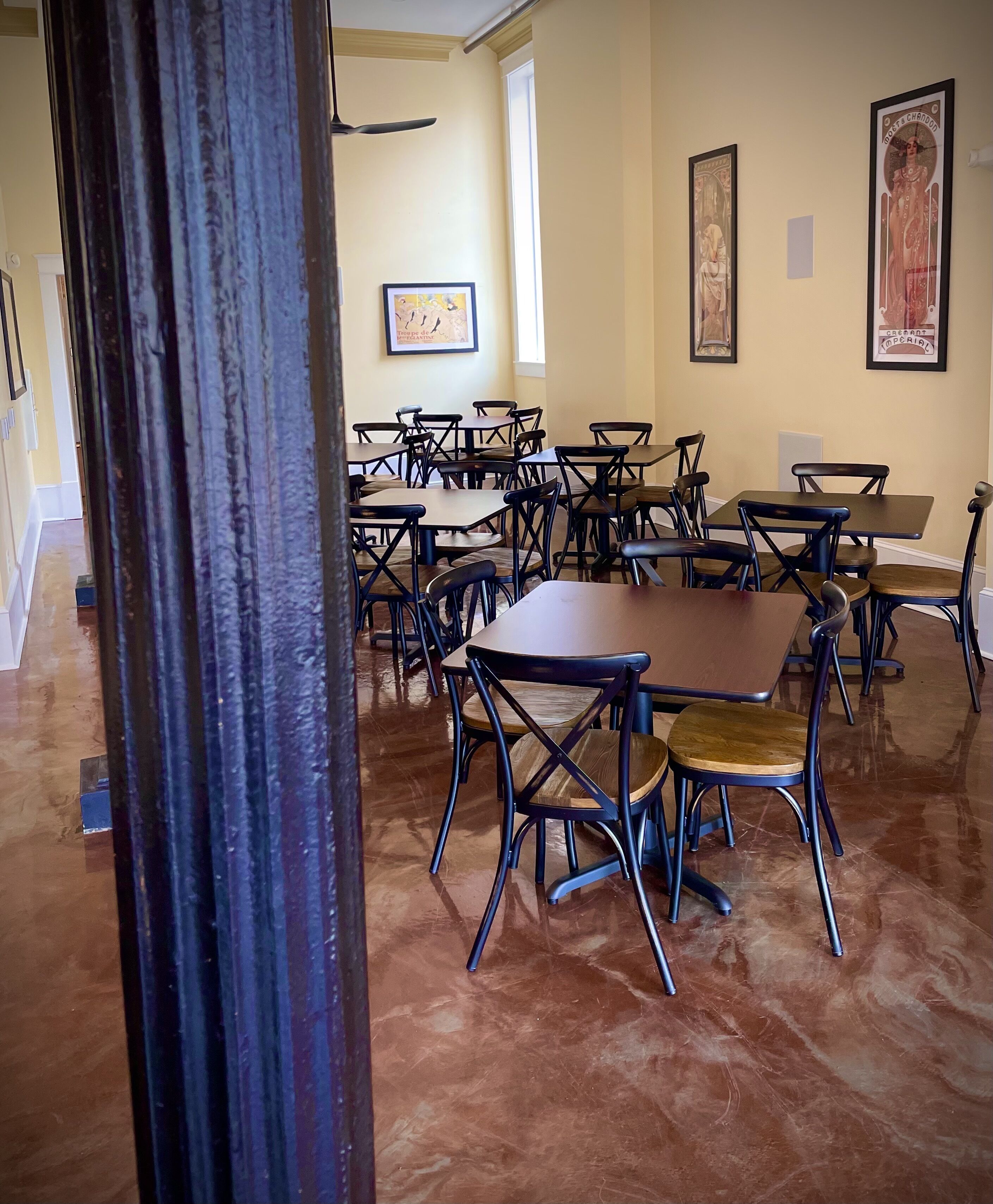 A conference room with multiple tables and chairs, a ceiling fan, and framed artwork on the walls.